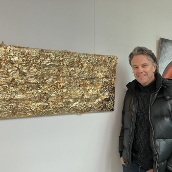 Ein Mann steht neben seinem Bild aus Blattgold.