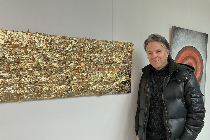 Ein Mann steht neben seinem Bild aus Blattgold.