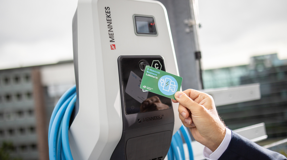 Ein Mann hält eine Ladekarte an eine Wallbox und schaltet so die Ladung für sein Elektroauto frei