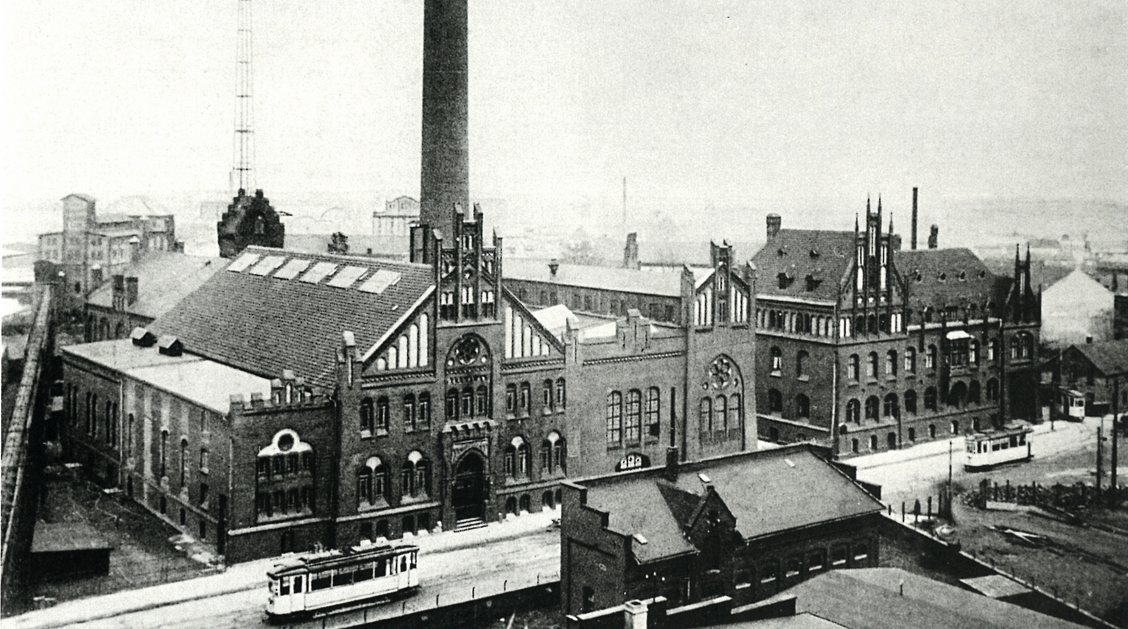 Das erste Elektrizitätswerk der Stadtwerke am Hafen, davor fährt eine Straßenbahn
