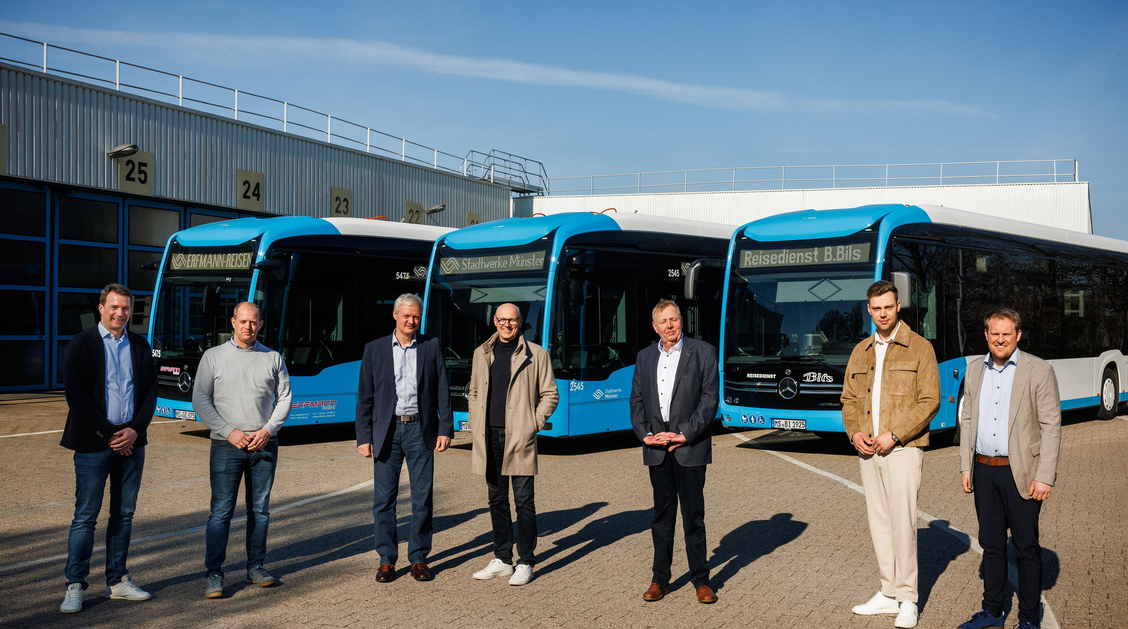 Personen stehen vor neuen Elektrobussen