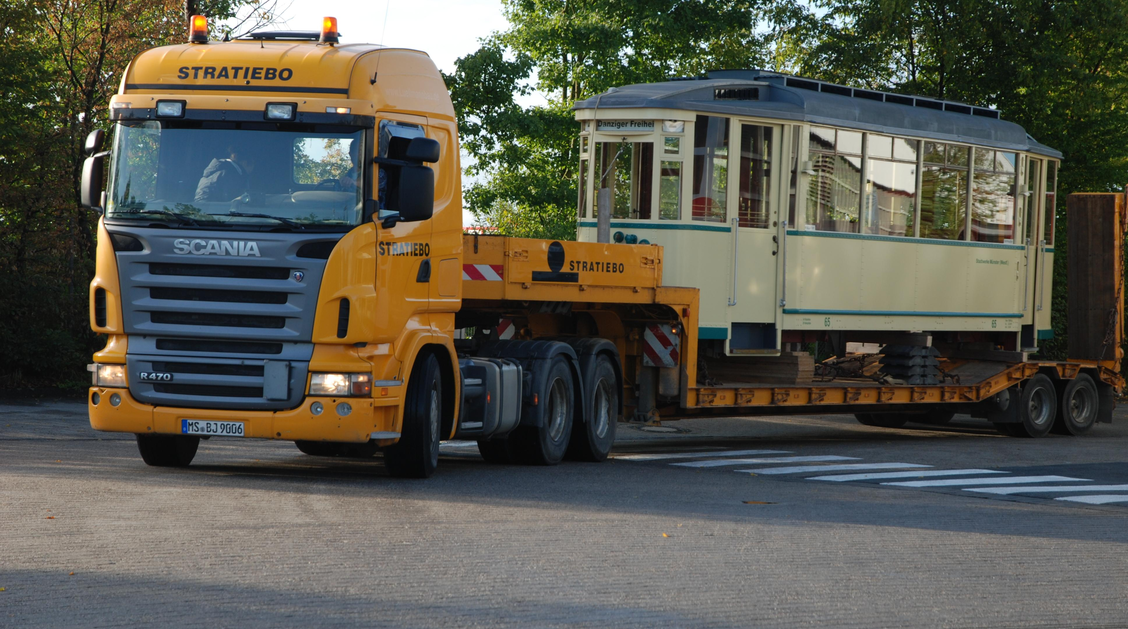 Ein historischer Straßenbahnwagen steht auf einem TIeflader
