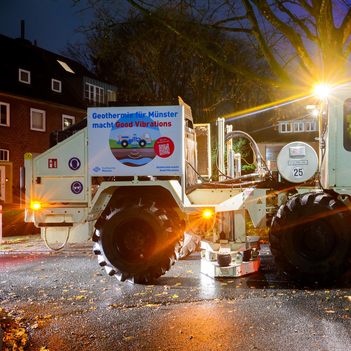 Das Bild zeigt ein großes Spezialfahrzeug mit einer absenkbaren Platte zwischen den beiden Achsen im münsterschen Geistviertel. Es ist Nacht. Das Fahrzeug ist beleuchtet. 
