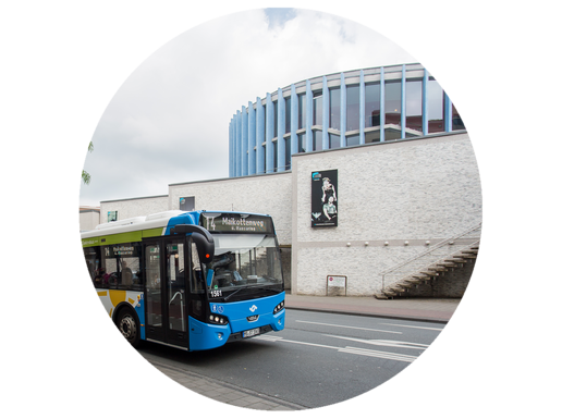 Stadtbus fährt vor einem Theatergebäude her.