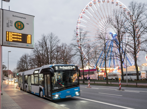 Stadtbus steht an einer Bushaltestelle und im Hintergrund sieht man den Send in Münster.