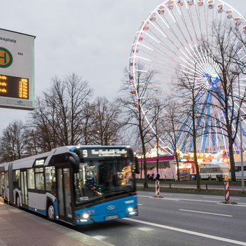 Stadtbus steht an einer Bushaltestelle und im Hintergrund sieht man den Send in Münster.