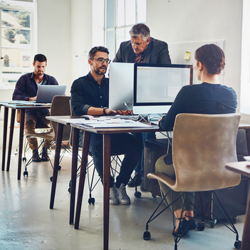 Mehrere Menschen arbeiten an einem Arbeitsplatz am Computer,