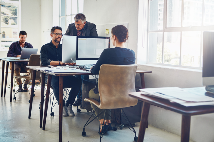 Mehrere Menschen arbeiten an einem Arbeitsplatz am Computer,