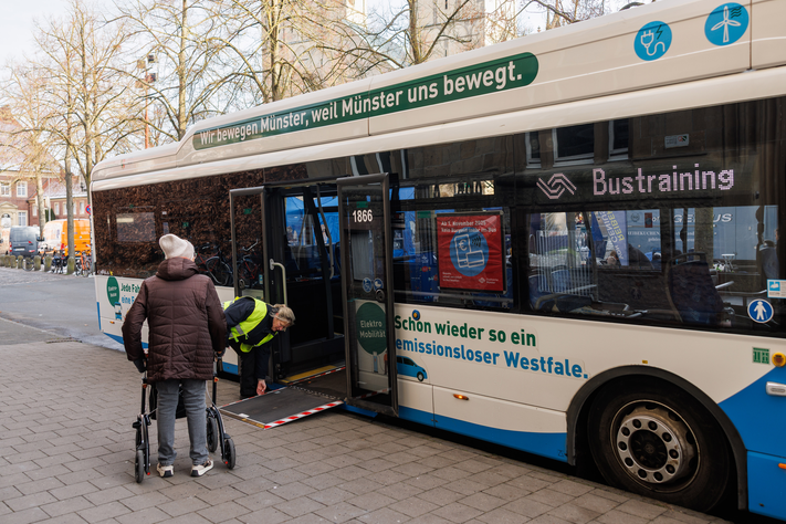 Eine Frau mit Rollator steigt in einen Stadtwerke-Bus ein.