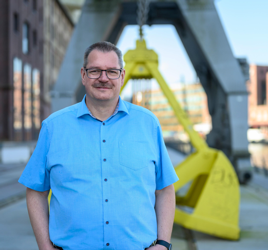 Ein Mann steht am Hafen und lächelt.