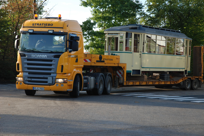 Ein historischer Straßenbahnwagen steht auf einem TIeflader