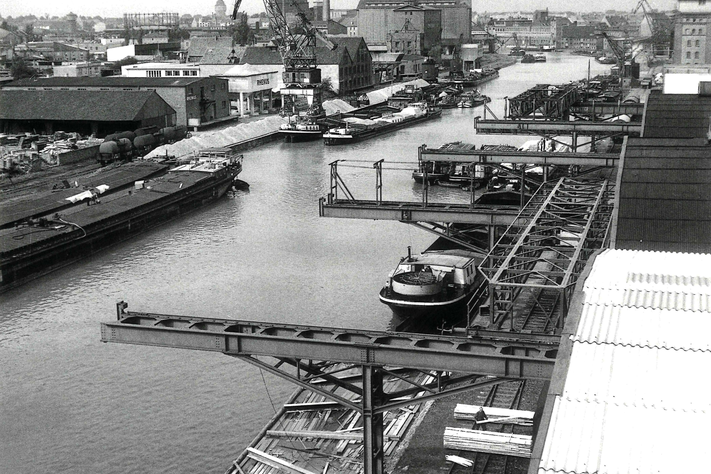 Ein aktiver Industriehafen mit mehreren Schiffen und Kränen in den 1950er Jahren