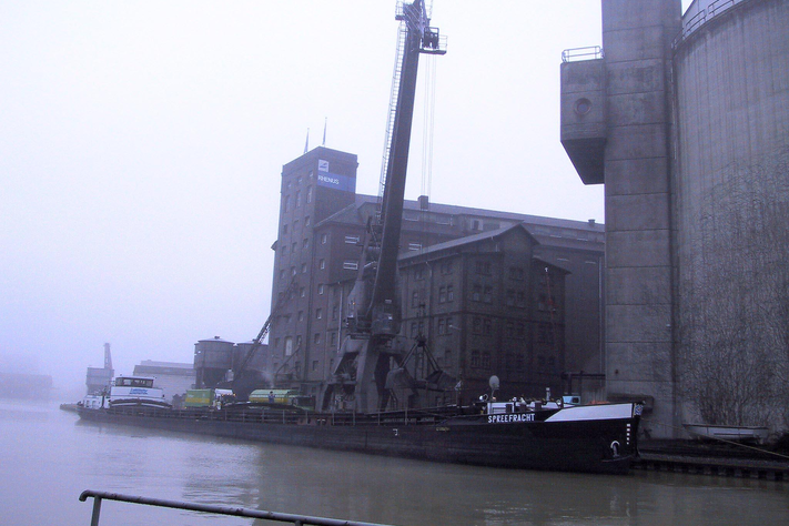 Ein Binnenschiff liegt im Hafen von Münster, ein Kran entlädt es