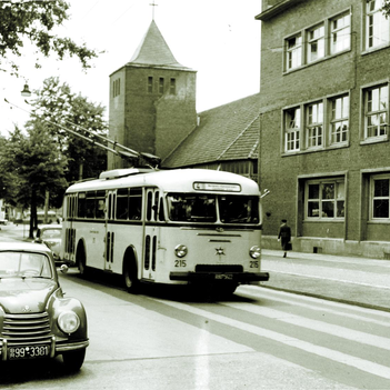 Ein Oberleitungsbus fährt über eine Straße, davor park ein Auto