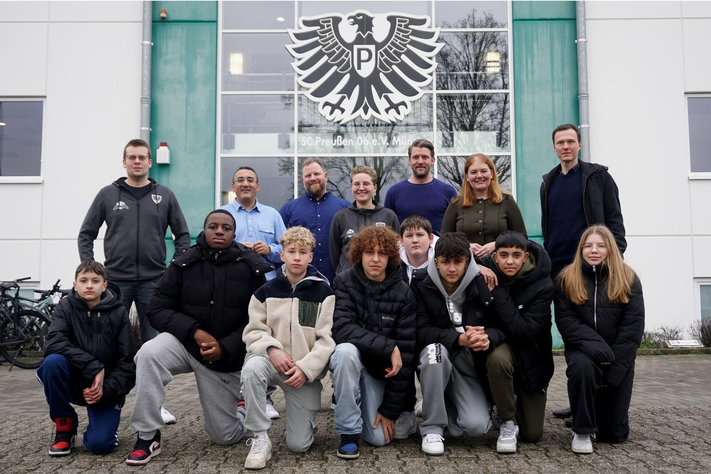 Eine Gruppe Jugendlicher steht als Gruppe vor dem LVM-Preußenstadion.