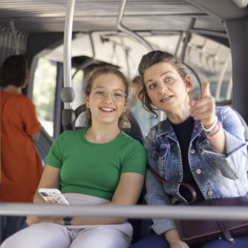 Ein Mädchen sitzt mit ihrer Mutter im Bus.
