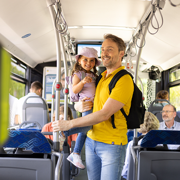 Vater mit kleiner Tochter auf dem Arm steht im Bus.