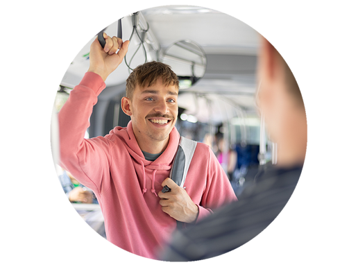 Junger Mann stehen im Bus und hält sich an einer Schlaufe fest.