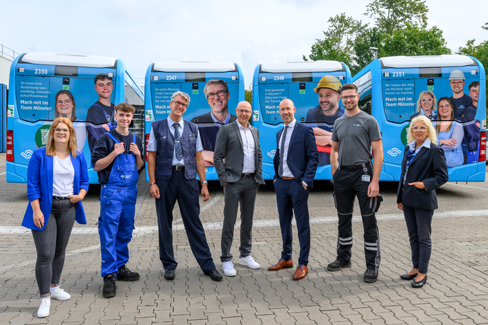 Mitarbeitende des Team Münster zeigen auf vier Bussen Gesicht, um neue Kolleginnen und Kollegen zu gewinnen.