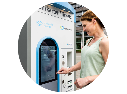 Eine Frau steht an einem Fahrkartenautomat.