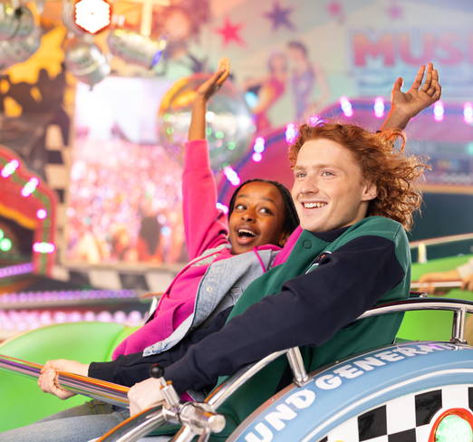 Ein junges Paar sitzt lachend in einem Discojet auf einer Kirmes.