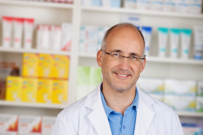Ein Apotheker steht hinter seiner Kasse.