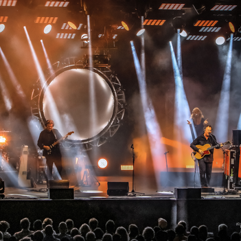 Eine Band steht auf einer beleuchteten Bühne. 