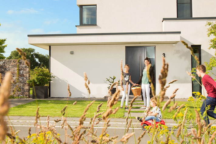 Eine sechsköpfige Familie spielt an einem sonnigen Tag vor Ihrem Haus auf der Straße und Garage