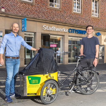 Das kostenlose Lastenrad Lotte kann bis Ende Juli im CityShop der Stadtwerke ausgeliehen werden. Darüber freuen sich Steffen Schmidt von der Lastenrad-Initiative „Lasse“ (r.) und CityShop-Leiter Marcel Braulik.