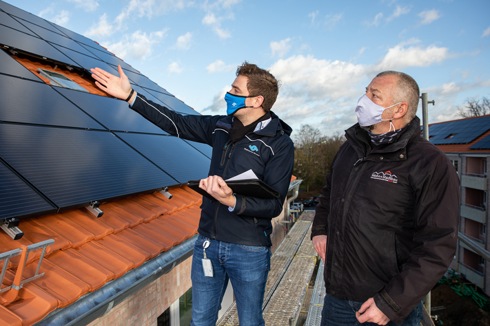 Bevor das Baugerüst entfernt wird, schauten sich Frederik Stroetmann (Stadtwerke Münster) und Andreas Jenschke (Wohn + Stadtbau) die neuen Photovoltaik-Anlagen an der Von-Stauffenberg-Straße noch einmal aus der Nähe an.