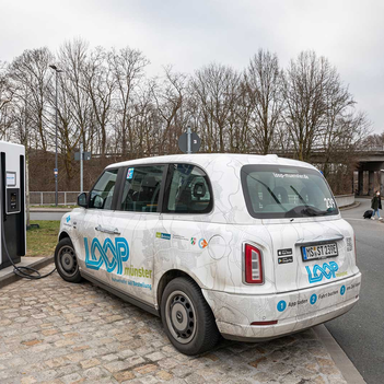 Ein Kleinbus von LOOPmünster lädt seine Batterien mit Ökostrom voll. Daneben ist ein freier Stellplatz zum Laden von privaten Elektroautos.