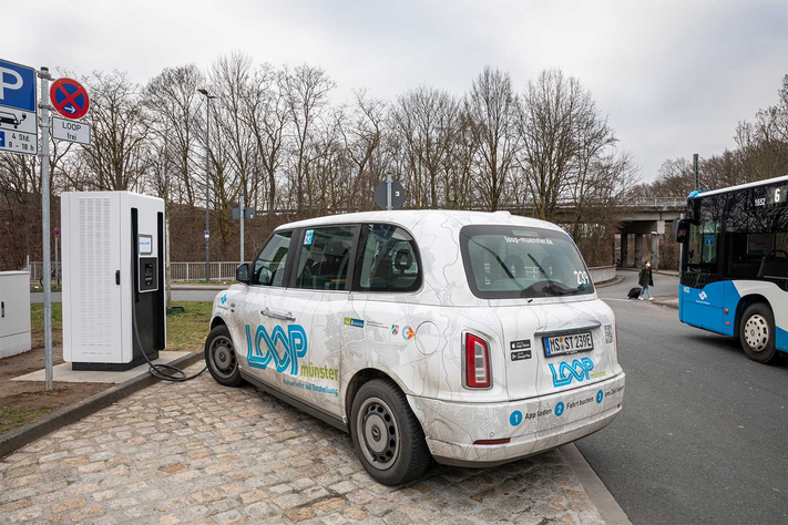 Ein Kleinbus von LOOPmünster lädt seine Batterien mit Ökostrom voll. Daneben ist ein freier Stellplatz zum Laden von privaten Elektroautos.