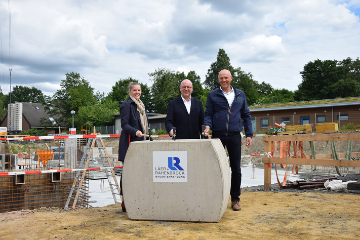 Auf der Südbad-Baustelle am Inselbogen klopfen Sportamtsleiterin Kerstin Dewaldt, Oberbürgermeister Markus Lewe und Stadtwerke-Geschäftsführer Frank Gäfgen eine Zeitkapsel im Grundstein fest.