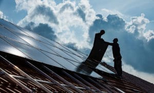 Zwei Menschen montieren eine Photovoltaikanlage auf einem Dach.